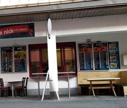 Fassade von Pick Nick mit Speisekarten-Tafeln, Stehtischen, Stühlen und einer Holzbank vor dem Lokal