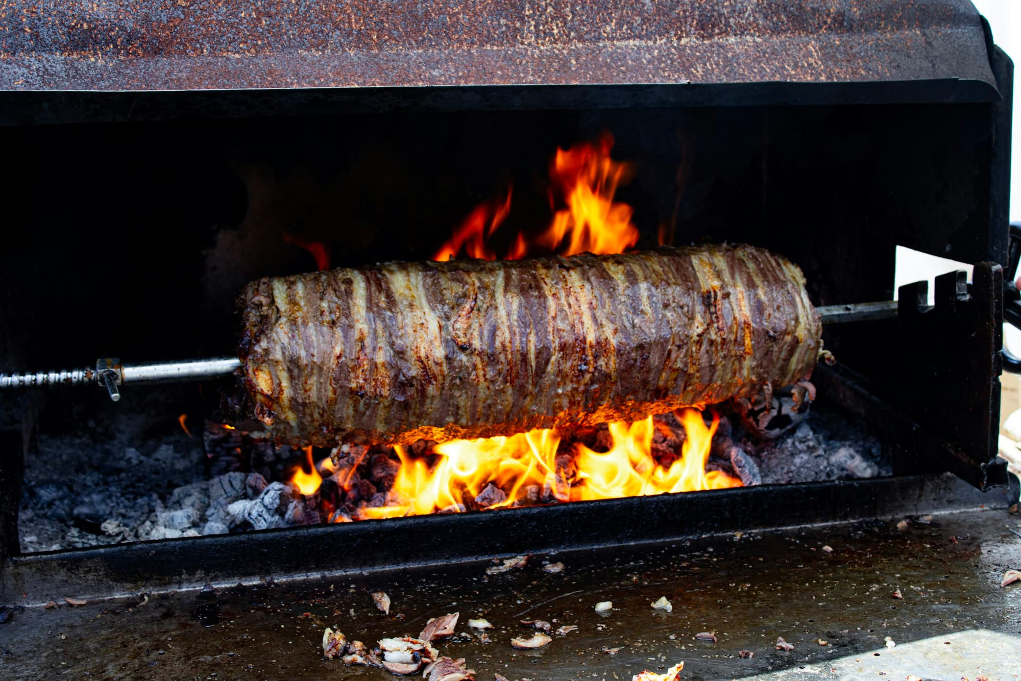 Fleischspieß dreht sich über offenem Feuer am Grill