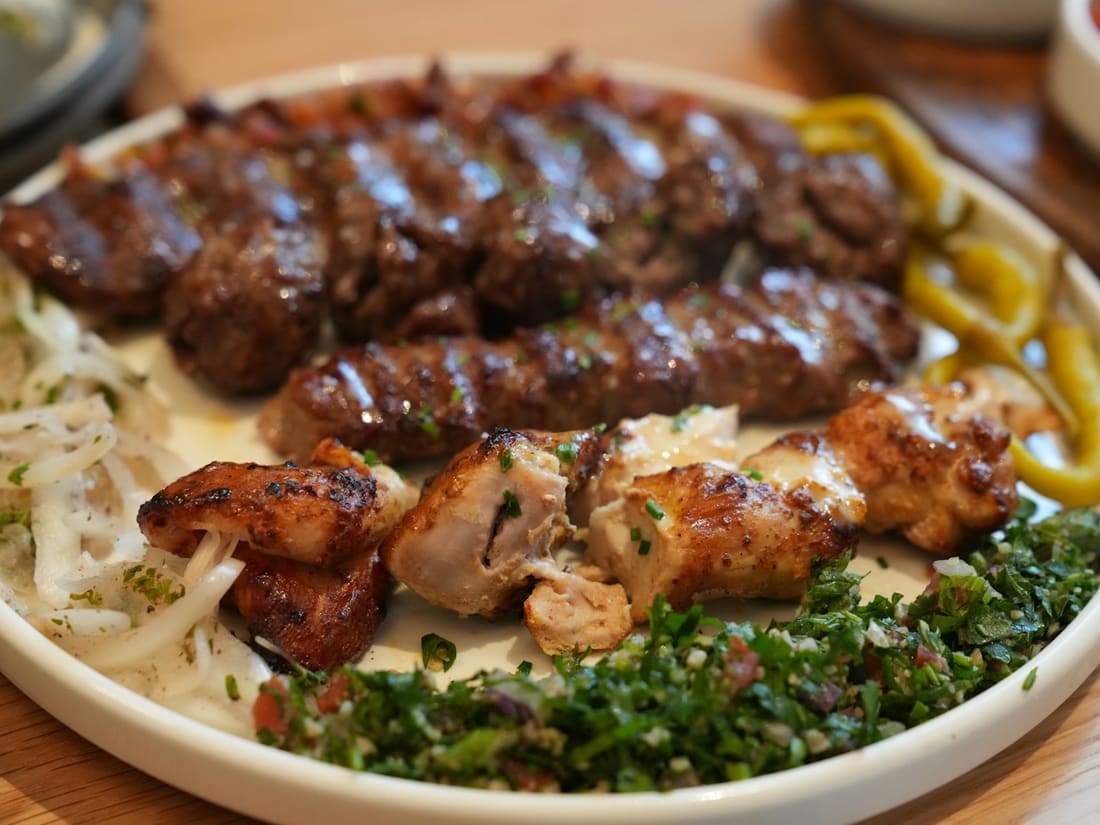 Teller mit gegrilltem Kebap, Hühnerspieß, Zwiebeln und Petersiliensalat