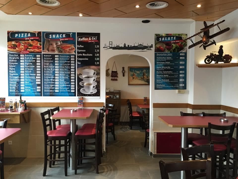 Gastraum von Pick Nick mit roten Tischen, Holzdecke und Speisekarten-Tafeln an der Wand
